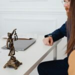 Cadre professionnel avec des avocats et une statue de Lady Justice discutant de documents juridiques.