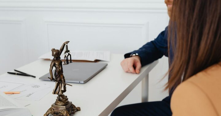 Cadre professionnel avec des avocats et une statue de Lady Justice discutant de documents juridiques.