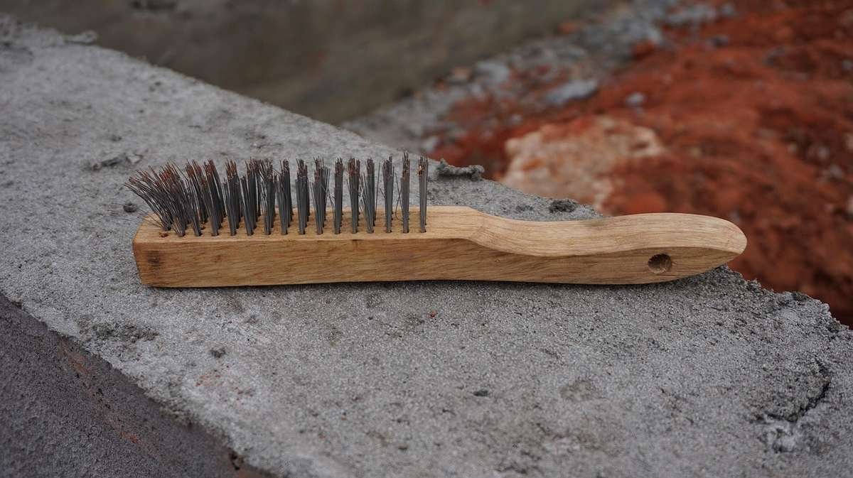 Brosses en bois et métal sur un rebord de béton, arrière-plan terré