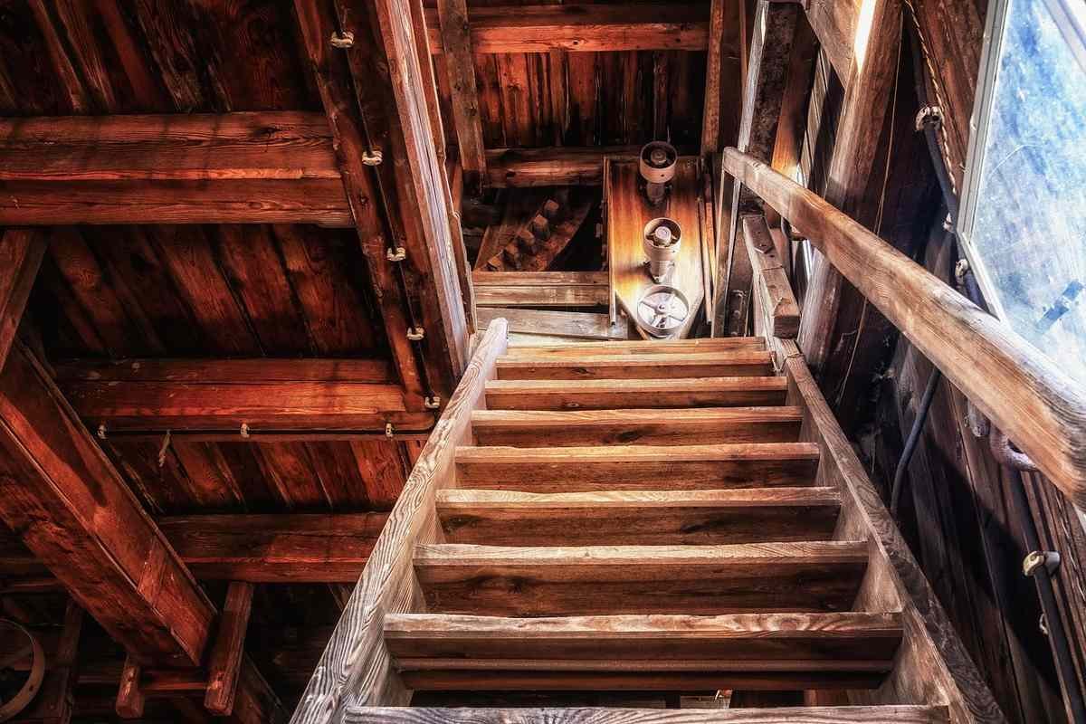 Escalier en bois avec main‑rail, poutres apparentes et personne assise