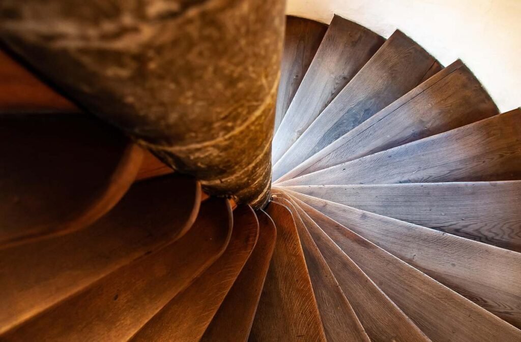 Vue du dessous d'un escalier en bois tournant autour d'une colonne