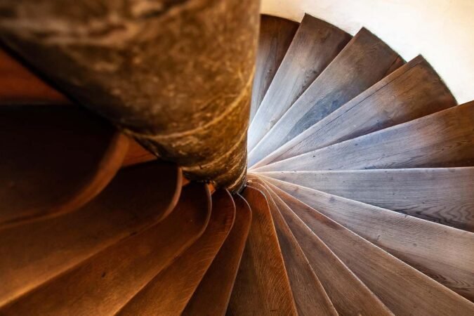 Vue du dessous d'un escalier en bois tournant autour d'une colonne
