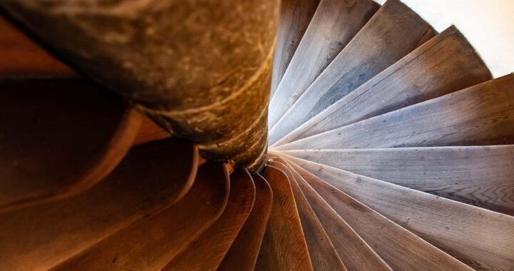 Vue du dessous d'un escalier en bois tournant autour d'une colonne