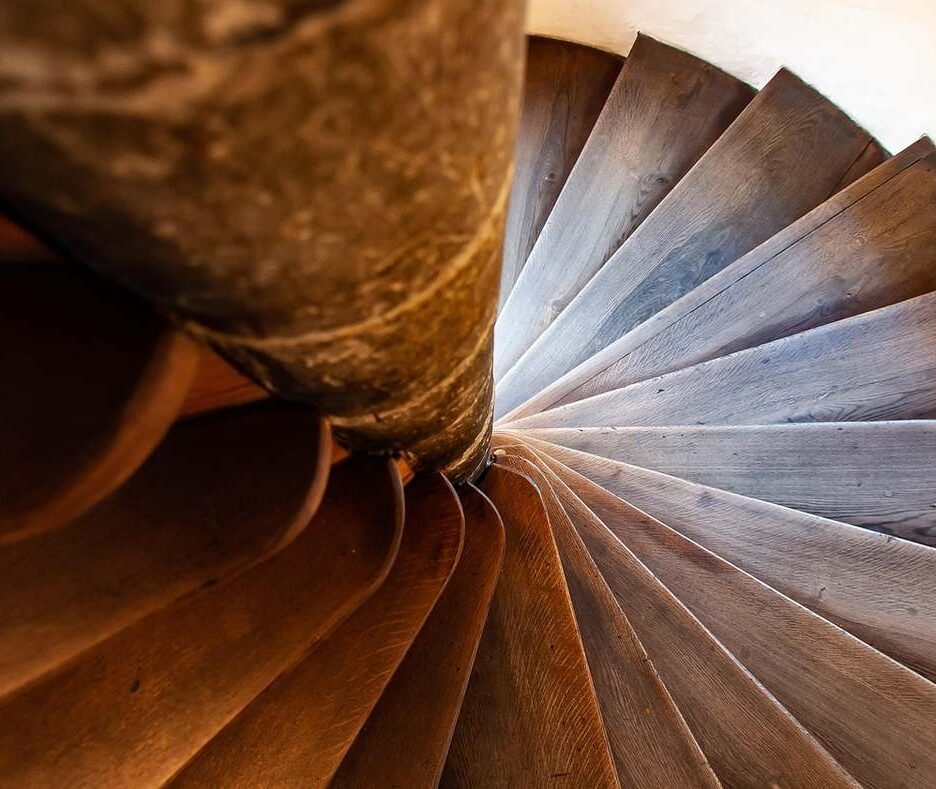 Vue du dessous d'un escalier en bois tournant autour d'une colonne