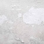 Peinture blanche qui s'écaille sur un mur texturé, montrant sous-couche