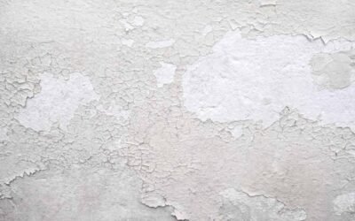 Peinture blanche qui s'écaille sur un mur texturé, montrant sous-couche
