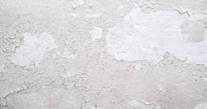 Peinture blanche qui s'écaille sur un mur texturé, montrant sous-couche
