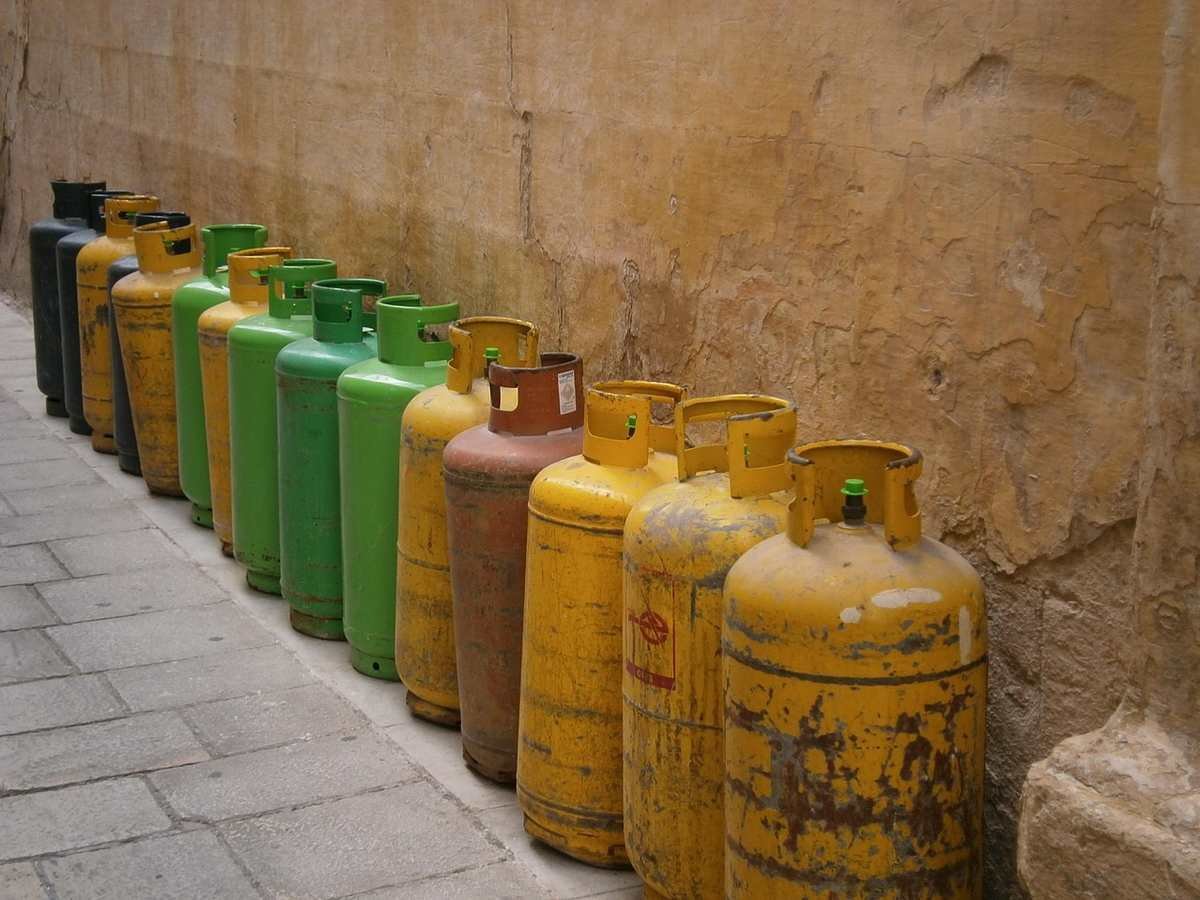 Bouteilles de gaz colorées rangées contre un mur de brique