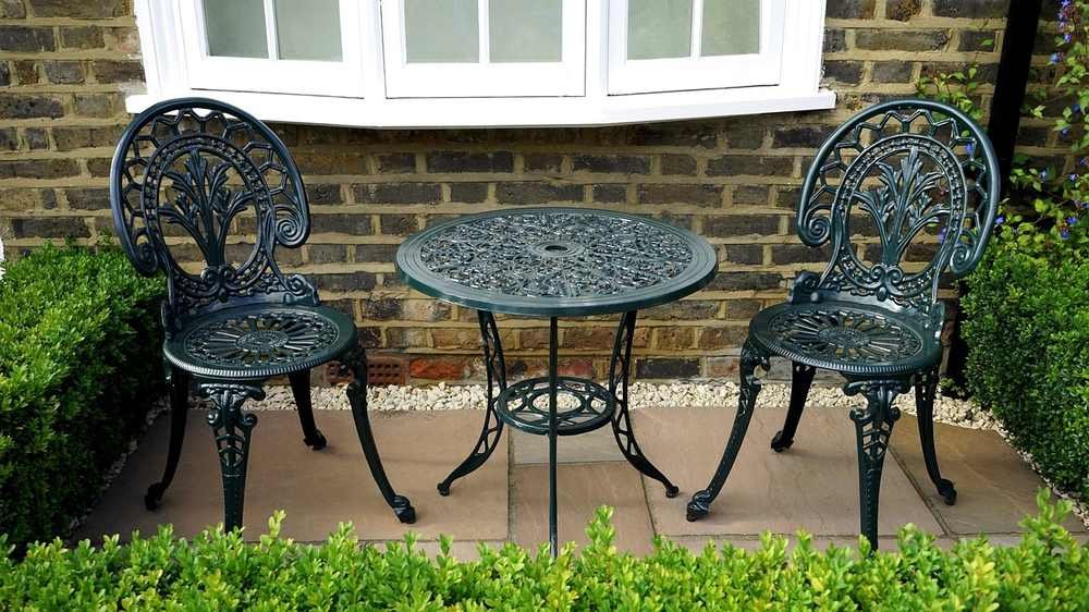 Deux chaises en fer forgé, petite table ronde, mur en brique, jardin